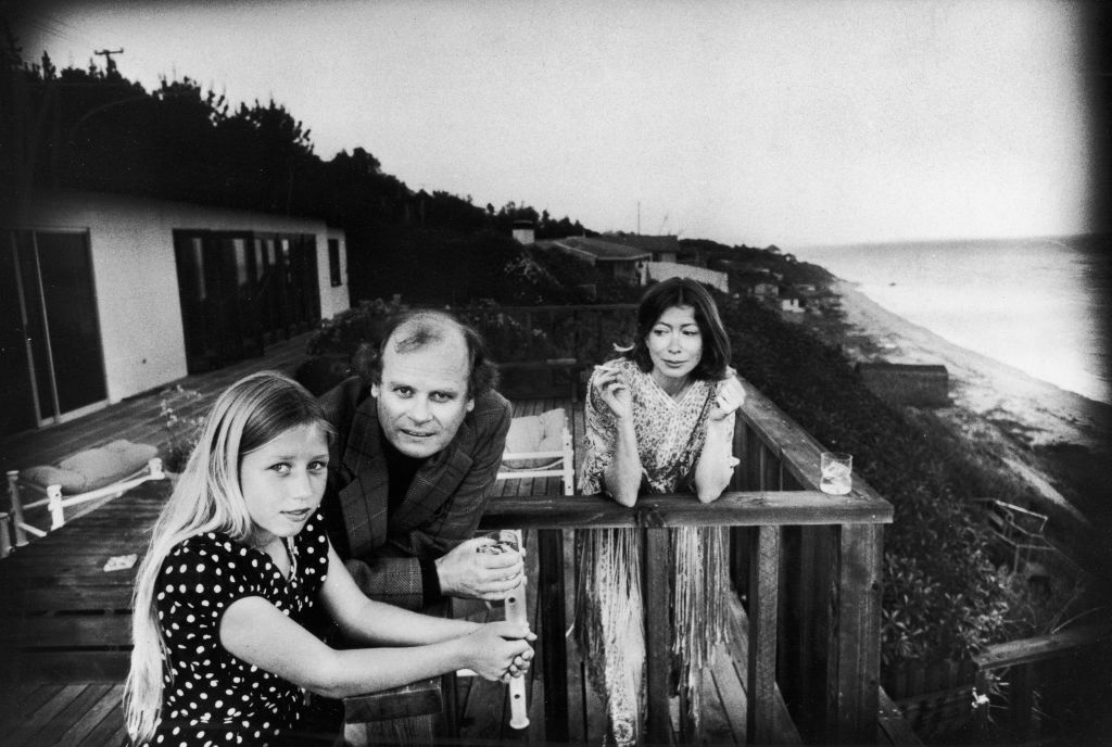 On a patio deck overlooking the ocean, Quintana Roo Dunne (L) leans on a railing with her parents, American authors and scriptwriters John Gregory Dunne (1932 - 2003) and Joan Didion, Malibu, California, 1976.   (Photo by John Bryson/Getty Images)