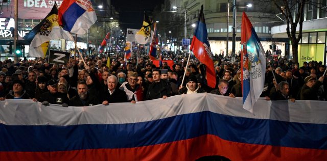 People wave Russian and Serbian flags during a rally in Belgrade. Credit: Getty