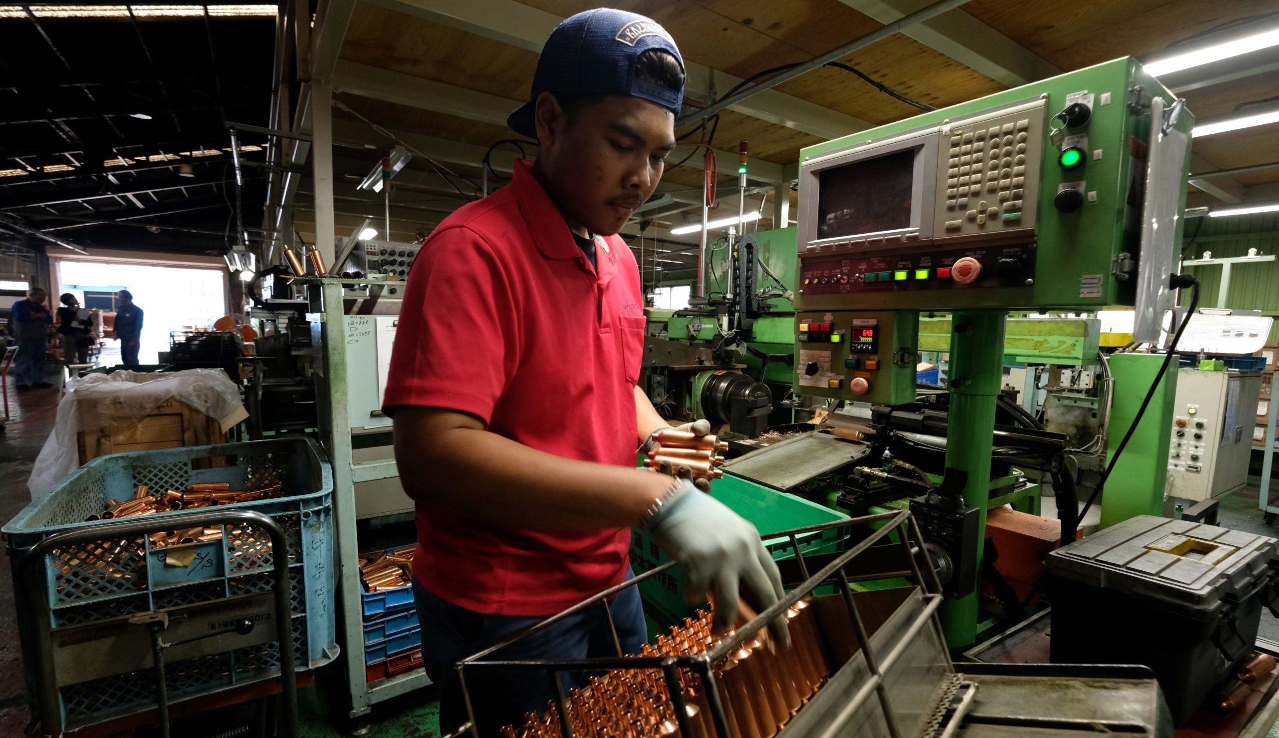An Indonesian worker processing copper pipes in a Japanese factory. Credit: Getty.
