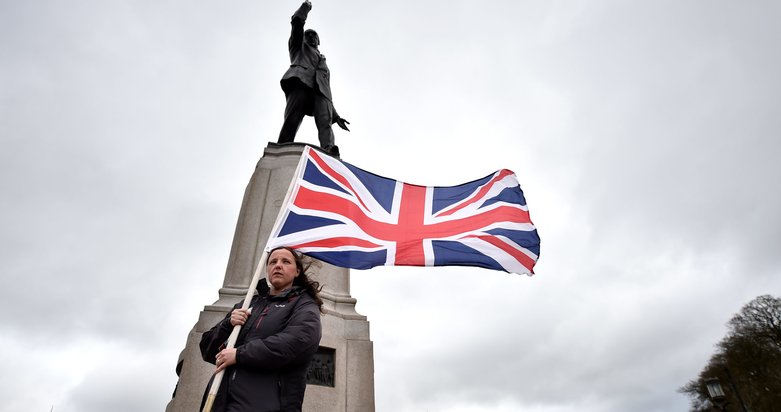 A unionist protestor stands under Edward Carson’s statue at Stormont. Credit: Getty.