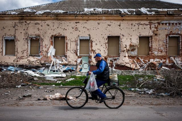 A man rides past a destroyed house in the village of Derhachi north of Kharkiv (DIMITAR DILKOFF/AFP via Getty Images)