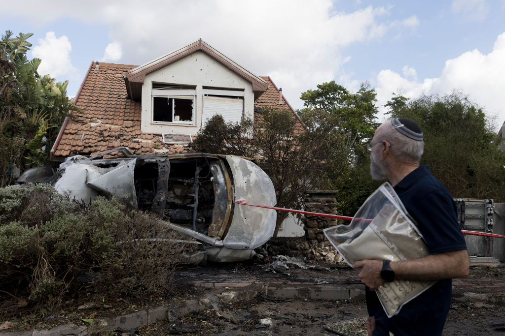 A man in northern Israel walks past a house hit by a rocket fired from Lebanon yesterday. Credit: Getty