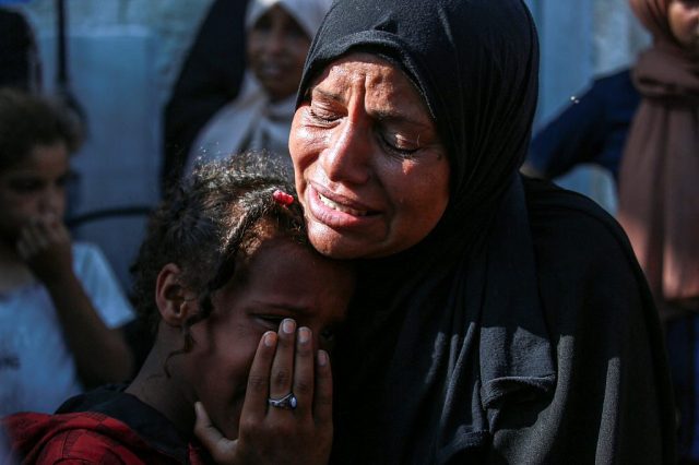 A Palestinian woman and child mourn the death of a loved one following Israeli bombardment last year. Credit: Getty